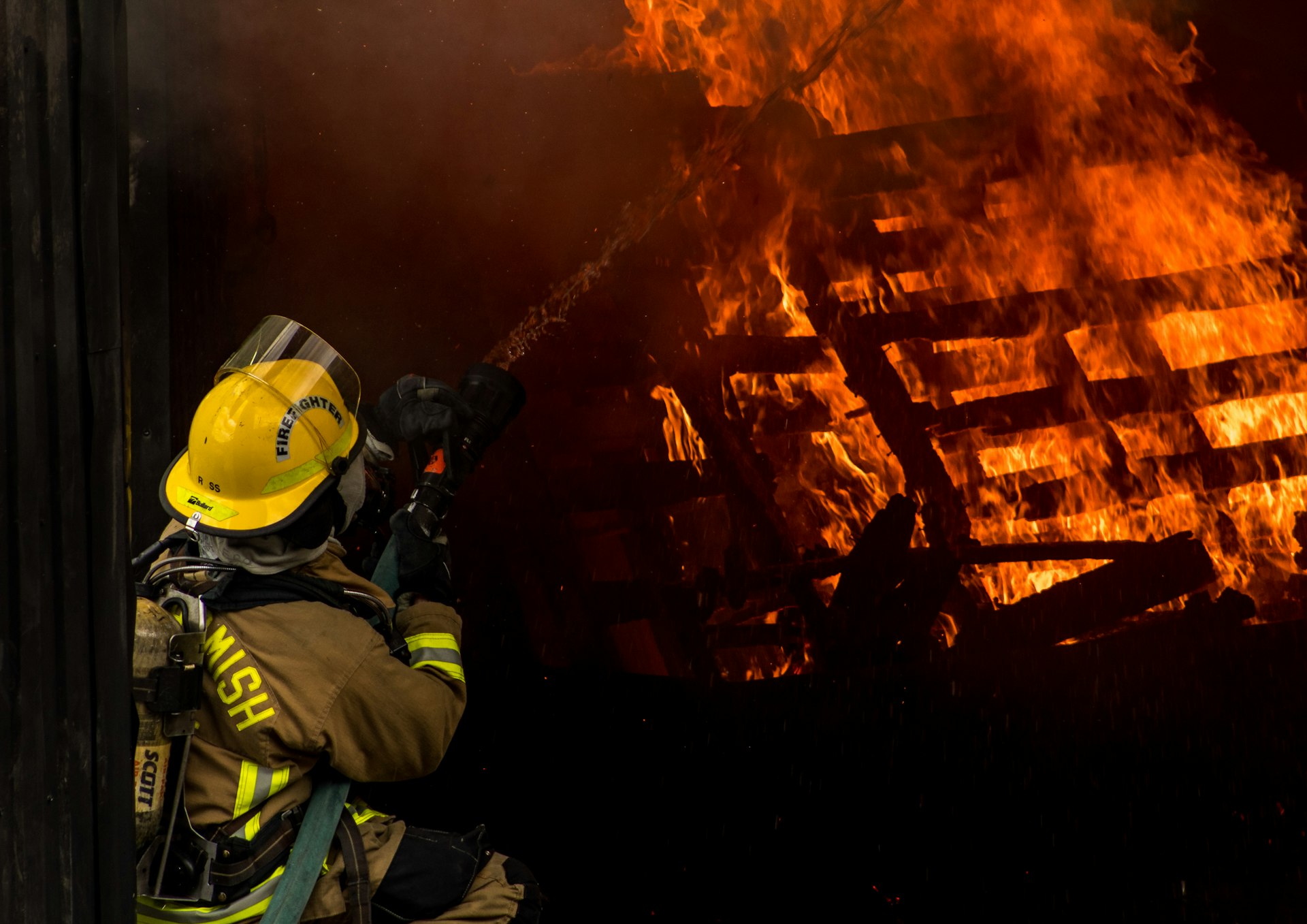 Firefighter directing a hose at a burning structure