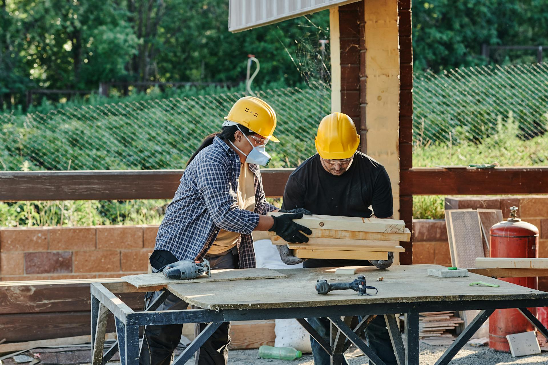 Workers cutting plywood on a sawhorse