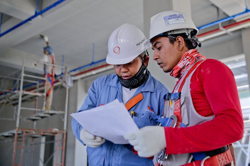 Two workers in hard hats reviewing plans on a construction site